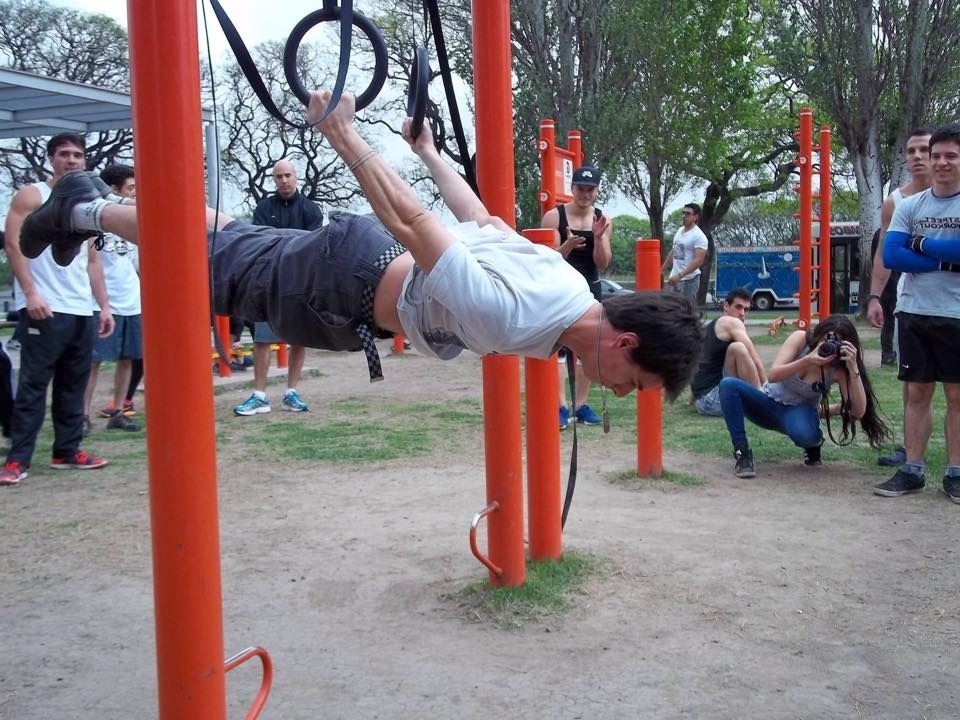 Christian García haciendo un ejercicio en las anillas mientras el grupo mira
